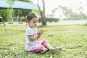 wenig asiatisch Mädchen üben Achtsamkeit Meditation draussen im ein Park. foto