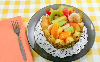 frischer Obstsalat mit Kiwi, Banane, Pfirsich, Orange, Rotorange, Aprikose und Melone in handgemachter Ananasschale. foto