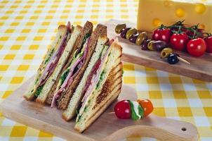 Club-Sandwich mit Schinken, Salami, Räucherfleisch, Käse, Salat und Rucola.Toast-Sandwich-Zubereitung. foto