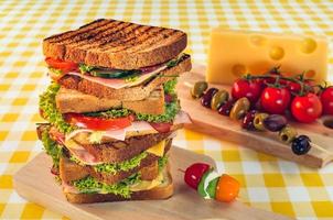 Club-Sandwich mit Schinken, Salami, Räucherfleisch, Käse, Salat und Rucola.Toast-Sandwich-Zubereitung. foto