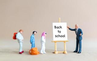 Lehrer und Schüler in der Nähe von Leinwand auf Staffelei mit dem Wort zurück zur Schule foto