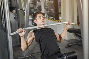 fitter Mann, der im Fitnessstudio an einer Maschine trainiert foto
