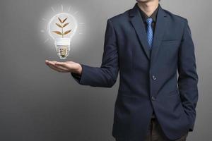 Ideenlampe in der Hand des Geschäftsmannes retten Erdkonzept