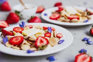 Pfannkuchen-Müsli, trendiges Essen. Mini-Getreidepfannkuchen mit Butter, Honig und Erdbeeren.