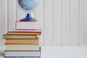 Stapel von Lehrbüchern und der Welt auf weißem Hintergrund. Bildungskonzept. foto