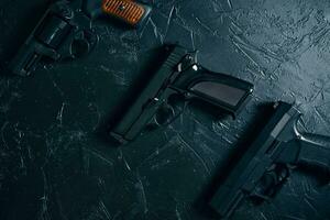 drei Pistolen auf schwarzem Tisch.