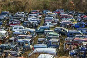 viele Autos im ein Schrottplatz mit Motorhauben oben und Teile fehlt mögen Reifen foto