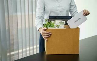 Geschäft Frau Senden Rücktritt Brief und Verpackung Zeug zurücktreten drücken oder Tragen Geschäft Karton Box durch Schreibtisch im Büro. Veränderung von Job oder gefeuert von Unternehmen. foto