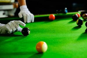 des Mannes Hand und Stichwort Arm spielen Snooker Spiel oder vorbereiten Zielen zu schießen Schwimmbad Bälle auf ein Grün Billard- Tisch. bunt Snooker Bälle auf Grün Fries. foto