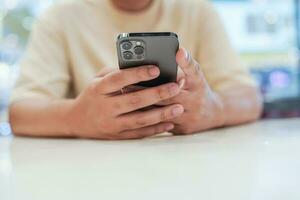 entspannt jung asiatisch Mann mit Clever Telefon Ausgaben Zeit Überprüfung Nachrichten Sozial Medien. foto