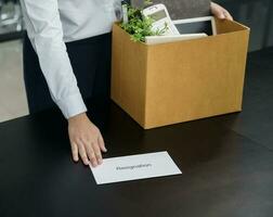 Geschäft Frau Senden Rücktritt Brief zu Boss und halten Zeug zurücktreten drücken oder Tragen Karton Box durch Schreibtisch im Büro foto