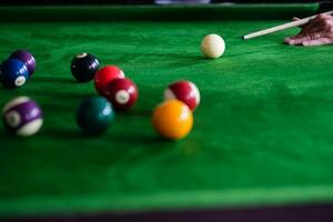 des Mannes Hand und Stichwort Arm spielen Snooker Spiel oder vorbereiten Zielen zu schießen Schwimmbad Bälle auf ein Grün Billard- Tisch. bunt Snooker Bälle auf Grün Fries. foto