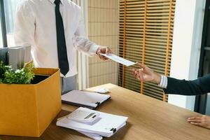 Verlassen Job Geschäft Mann Senden Rücktritt Brief und Verpackung Zeug zurücktreten drücken oder Tragen Geschäft Karton Box im Büro. Veränderung von Job oder gefeuert von Unternehmen. foto