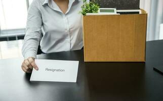 Geschäft Frau Senden Rücktritt Brief zu Boss und halten Zeug zurücktreten drücken oder Tragen Karton Box durch Schreibtisch im Büro foto