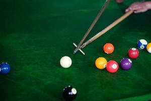 des Mannes Hand und Stichwort Arm spielen Snooker Spiel oder vorbereiten Zielen zu schießen Schwimmbad Bälle auf ein Grün Billard- Tisch. bunt Snooker Bälle auf Grün Fries. foto