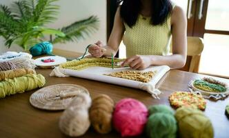 schlagen Nadel. asiatisch Frau Herstellung handgemacht Hobby Stricken im Studio Werkstatt. Designer Arbeitsplatz handgemacht Kunst Projekt DIY Stickerei Konzept. foto