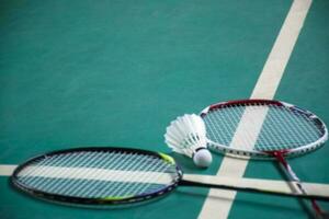 Cremeweißer Badminton-Shuttlecock und Schläger auf dem Boden im Indoor-Badmintonplatz, Kopierraum, weicher und selektiver Fokus auf Federbälle. foto