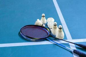 Cremeweißer Badminton-Shuttlecock und Schläger auf dem Boden im Indoor-Badmintonplatz, Kopierraum, weicher und selektiver Fokus auf Federbälle. foto