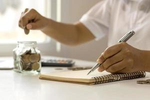 Geld sparende Idee. die Hand einer Frau, die einen Stift hält, um Ausgaben im Haus aufzuschreiben.