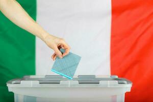 weiblich Hand hält Abstimmung Über Abstimmung Kasten. Italienisch Flagge im das Hintergrund. foto