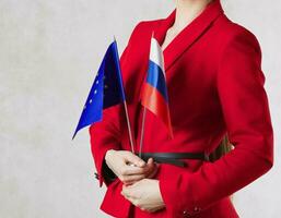 ein jung Frau zwischen 30 und 40 Jahre alt halt zwei Flaggen von EU und Russland. foto