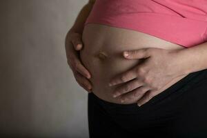 jung schwanger Frau berührt ihr Bauch. dramatisch Licht. foto