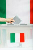 weiblich Hand hält Abstimmung Über Abstimmung Kasten. Italienisch Flagge im das Hintergrund. foto