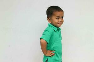 Porträt von ein süß wenig asiatisch Junge suchen beim Weiß Raum und lächelnd, auf das Weiß Hintergrund foto