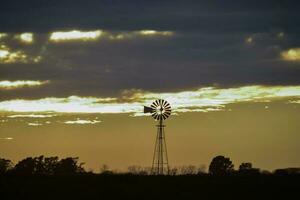 Landschaft mit Windmühle beim Sonnenuntergang, Pampas, Patagonien, Argentinien foto