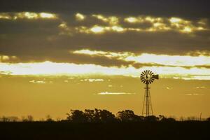 Landschaft mit Windmühle beim Sonnenuntergang, Pampas, Patagonien, Argentinien foto