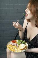 zufrieden Frau schmeckt Omelette mit Truthahn und Gemüse foto