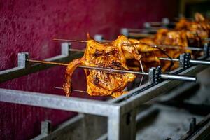 Nahansicht von Braten ein ganze Hähnchen im ein einfach Grill im Asien foto