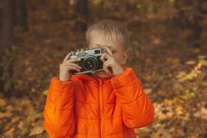 Junge mit retro Kamera nehmen Bilder draussen im Herbst Natur. Freizeit und Fotografen Konzept foto