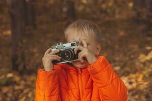 Junge mit retro Kamera nehmen Bilder draussen im Herbst Natur. Freizeit und Fotografen Konzept foto