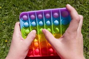 buntes Anti-Stress-Sinneszappel-Push-Pop-It-Spielzeug in Kinderhänden foto