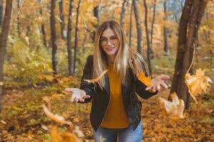 glücklich Lachen jung Frau werfen Blätter im Herbst Park. fallen Jahreszeit foto