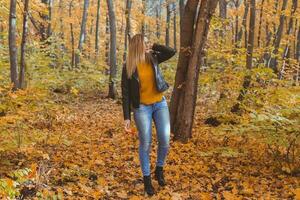 Mädchen hält gefallen Blätter und Spaziergänge im Herbst Park. saisonal Konzept. foto