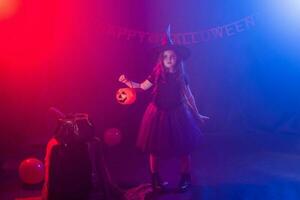 wenig Mädchen hält Kürbis Jack auf Halloween Urlaub. Kind Mädchen tragen Hexe Kostüm. Fantasie, Fee Geschichte und Maskerade Konzept. foto