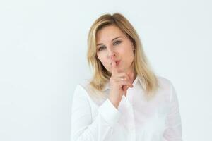 schön jung kaukasisch Frau isoliert auf Weiß Studio Hintergrund halt Finger beim Lippen Fragen Sein Leise ruhig. tausendjährig weiblich aussehen beim Kamera sagen Teilen Geheimnis, bekannt geben Geheimnis Verkauf oder Rabatt foto