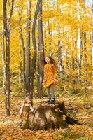 wenig Kind Mädchen mit Herbst Orange Blätter im ein Park. Lebensstil, fallen Jahreszeit und Kinder Konzept. foto