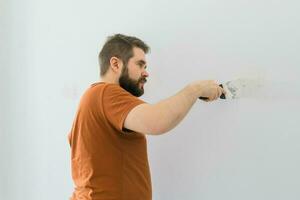 Mann glättet Mauer Oberfläche mit ein Mauer Schleifer. männlich schleifen ein Weiß Gips Mauer - - Renovierung und Renovierung Konzept foto