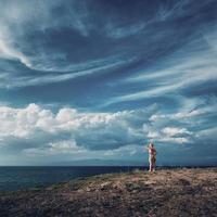 blonde Frau, die oben auf dem Hügel steht und über das Meer schaut. schöner Himmel über der Ägäis, Halbinsel Kassandra, Griechenland. foto