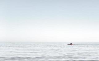 Mann, der auf dem sehr ruhigen Wasser auf dem Meer Kajak fährt. Mann Kajakfahren am frühen Nachmittag auf der Ägäis, Griechenland. foto