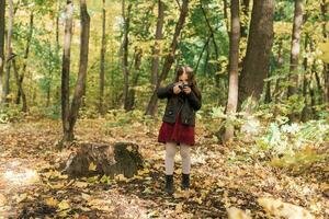 Kind Mädchen mit ein altmodisch Kamera im Herbst Natur. Fotograf, fallen Jahreszeit und Freizeit Konzept. foto