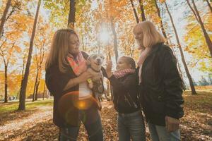 Oma und Mutter mit Enkelin haben Spaß mit Hund im Herbst Jahreszeit. Generation, Freizeit und Familie Konzept foto