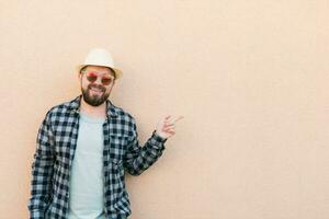 gut aussehend kaukasisch Mann tragen Sommer- Hut und Plaid Hemd lächelnd glücklich in der Nähe von Mauer mit Kopieren Raum - - Reise Urlaube und Sommer- Urlaub Konzept foto