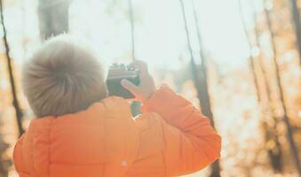 Junge mit retro Kamera nehmen Bilder draussen im Herbst Natur. Freizeit und Fotografen Konzept foto