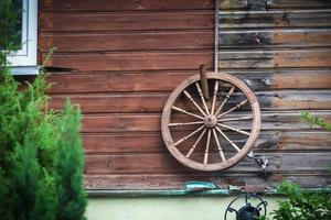 großes altes Holzrad, das an der Holzbrettwand eines Landhauses hängt foto