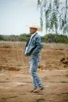 Cowboy tragen Jeans und ein Hut, Stehen unter das Himmel mit flauschige Wolken, Arbeiten auf ein Bauernhof foto