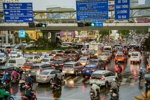 ho Chi Minh, viet nam - - 24 April 2023 Vietnamesisch Menschen tragen Helm und Regenjacke Reiten Motorrad im schwer Regen und der Verkehr Marmelade. foto